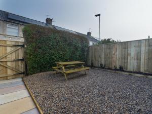 a wooden picnic table in a backyard with a fence at Chestnut House- 2 Bedroom house in Ashington, Northumberland in Ashington