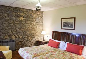 a bedroom with a stone wall and a bed with red pillows at Hotel Los Caspios in Colunga