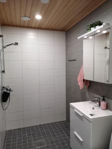 La salle de bains est pourvue d'un lavabo blanc et d'une douche. dans l'établissement Aurinkoranta D6, à Kalajoki