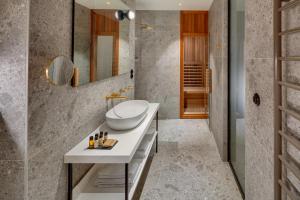 a bathroom with a sink, mirror, and bath tub at Hotel Leonardo & Bookquet Prague in Prague