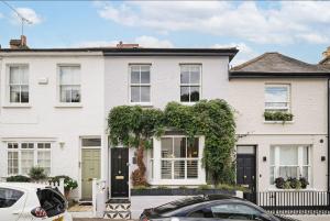 a white house with cars parked in front of it at Unique Chic Two Bed House Richmond in Richmond upon Thames