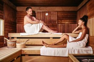 un homme et une femme assis dans un sauna dans l'établissement Parkhotel Quellenhof Aachen, à Aix-la-Chapelle