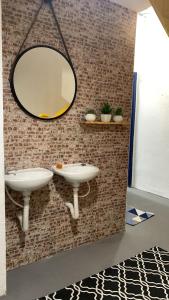 Baño con 2 lavabos y espejo en la pared en Vilarejo Hostel Pinheiros Guest House, en São Paulo