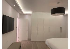 a bedroom with a bed and a flat screen tv at Hestia Travel Mayfair London in London