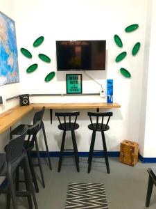 a desk with chairs and a computer monitor on a wall at Vilarejo Hostel Pinheiros Guest House in Sao Paulo