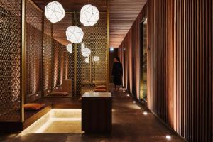 若特阿赫-埃根Spa & Resort Bachmair Weissach, LUXURY FAMILY RESORT的一名男子带着桌子和灯走在走廊上