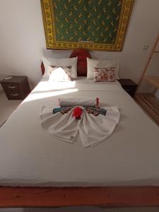 Una cama con sábanas blancas y flores rojas. en Jua Apartments, en Kiwengwa