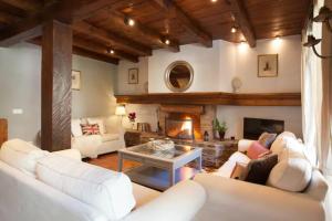 a living room with white couches and a fireplace at Tarter Chalets Apartaments in El Tarter