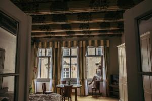 a woman sitting in a window taking a picture at Residence Thunovska in Prague