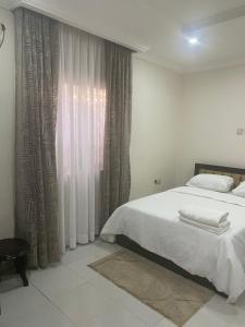 a bedroom with a bed and a window with curtains at Our Nice Home in Kaduna