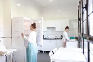 two women standing in a kitchen writing on a whiteboard at Hostel Águilas Isla del Fraile in Águilas