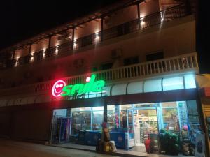 帕塔莫納斯的住宿－SMILE，夜间商店前有 ⁇ 虹灯标志