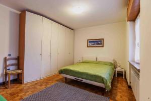 a bedroom with a green bed and white cabinets at Casa Alpina - Appartamento Aosta in Aosta