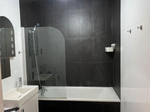 a bathroom with a tub and a sink and a mirror at Cosy Entire Apartment in WhiteChapel/Commercial Rd in London