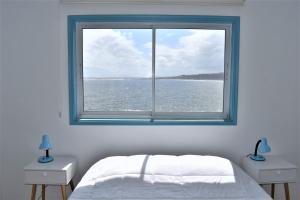 a bedroom with a window with a view of the water at Bahía Luz Hostal in Concón