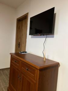 a flat screen tv on a wall with a wooden dresser at BUBLA CITY RANCH in Kopřivnice