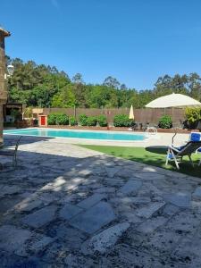 - une piscine avec 2 chaises et un parasol dans l'établissement Agradable casa rural en Galicia, à A Estrada