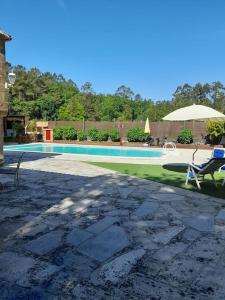 uma piscina com duas cadeiras e um guarda-sol em Agradable casa rural en Galicia em A Estrada