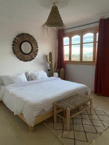 um quarto com uma grande cama branca e um espelho em Moana Surf Maroc em Tamraght Ouzdar