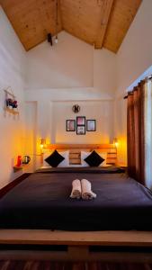a bedroom with a large bed with two slippers on it at Roamate Hostel, Old Manali in Manāli