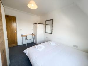 a bedroom with a white bed and a desk at The Bridge Apartments in Lowestoft