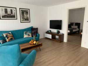 a living room with a blue couch and a television at Eifel24, neues und barrierefreies Appartement mit Terrasse in Schwirzheim