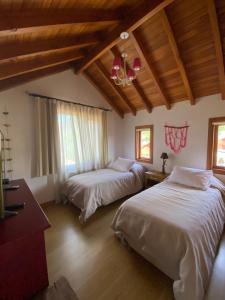 1 dormitorio con 2 camas y techo de madera en AMANCAY SUITES en San Martín de los Andes