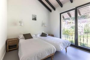 a bedroom with two beds and a large window at Larraetxea in Isla Becoa