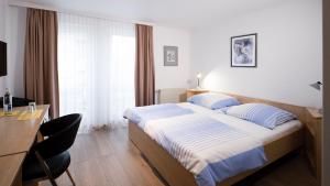 Una habitación de hotel con una cama, un escritorio y una mesa. en Brenzhotel Heidenheim, en Heidenheim an der Brenz