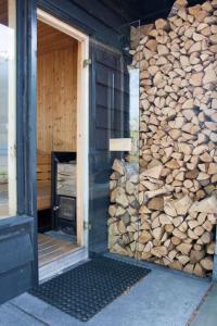 un edificio con un montón de madera al lado de una puerta en Wellness Lodge Ruigenhoek 13A - Sauna, Jacuzzi ! en De Zilk