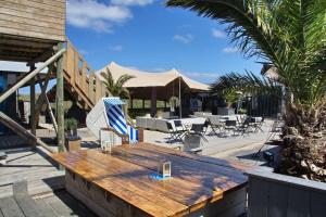 un patio con una mesa de madera, sillas y palmeras en Wellness Lodge Ruigenhoek 13A - Sauna, Jacuzzi ! en De Zilk
