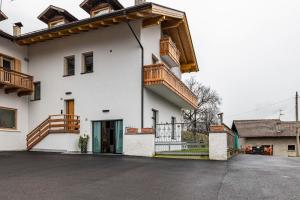 a white house with wooden balconies and a driveway at Loft Casa Facco in Bocenago