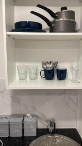 a kitchen shelf with bowls and dishes and a sink at London Studios in London