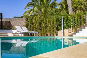 コスタ・デ・ラ・カルマにある3009 - Luxurious new villa in quiet area in Costa de la Calmaのヤシの木と椅子2脚が備わるスイミングプール