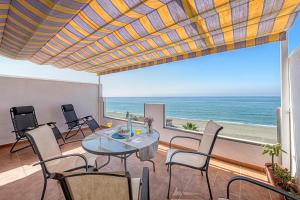 jadalnia ze stołem i krzesłami oraz oceanem w obiekcie WintowinRentals Amazing Front Sea View & Relax w mieście Torre de Benagalbón