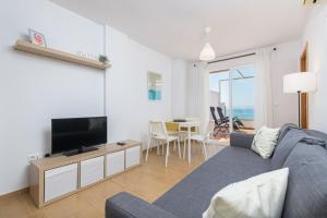 a living room with a blue couch and a television at WintowinRentals Amazing Front Sea View & Relax in Torre de Benagalbón