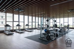 un gimnasio con cintas de correr y pesas en una habitación con ventanas en Bali Premier Suites Melaka en Melaka