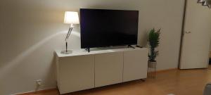 - une télévision à écran plat sur une armoire blanche avec une lampe dans l'établissement Keskustan kaksio, à Rovaniemi