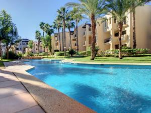 uma piscina com palmeiras em frente a um edifício em Roda Golf Resort - 9309 em San Javier