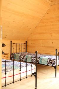 two beds in a room with a wooden wall at Osada Stasiowe Chaty in Stronie Śląskie