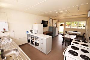 a kitchen with white appliances and a dining room with a table at Ranfurly Holiday Park & Motels in Ranfurly