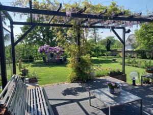 um jardim com uma pérgola de madeira e uma mesa com flores em B&B 't Pakhuis em Meteren