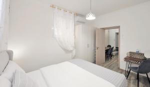 a white bedroom with a bed and a desk at Bella Ciao Guest House in Athens