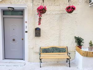 drewniana ławka siedząca przed budynkiem z drzwiami w obiekcie Bella Ciao Guest House w Atenach