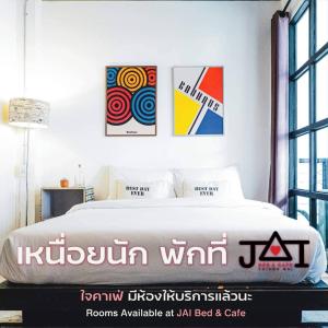 Schlafzimmer mit einem Bett mit Gemälden an der Wand in der Unterkunft JAI bed and cafe in Chiang Mai