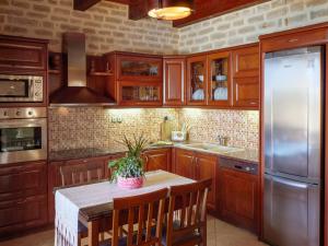 a kitchen with wooden cabinets and a table with a plant on it at Family-Friendly Villa Erofili with Pool, Childrens Area & BBQ! in Astérion