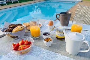 einen Tisch mit Frühstückszutaten und Getränken neben einem Pool in der Unterkunft Clos des marais in Loix