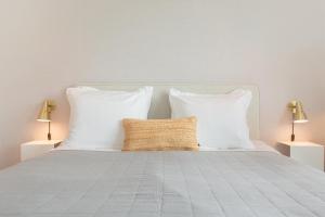 a bedroom with a bed with white pillows and two lamps at Hello Zeeland - Summum Suites in Domburg