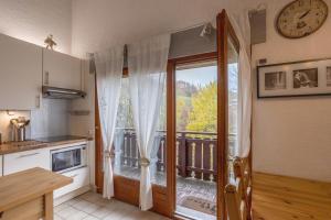 a kitchen with a door open to a balcony at Le Forchat - proche des pistes in Bellevaux