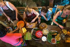 a group of women standing around a table preparing food at Lovina Central Hostel in Lovina